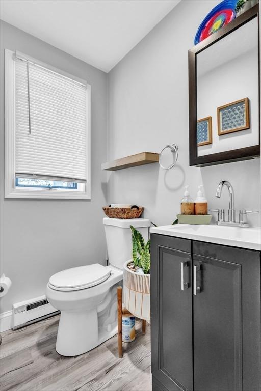 bathroom with vanity, toilet, wood finished floors, and a baseboard radiator