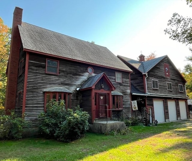 view of front of house with a front yard, roof with shingles, and a chimney