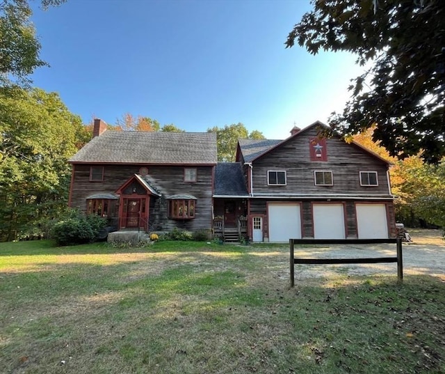 view of front of house featuring driveway, an attached garage, a chimney, and a front lawn