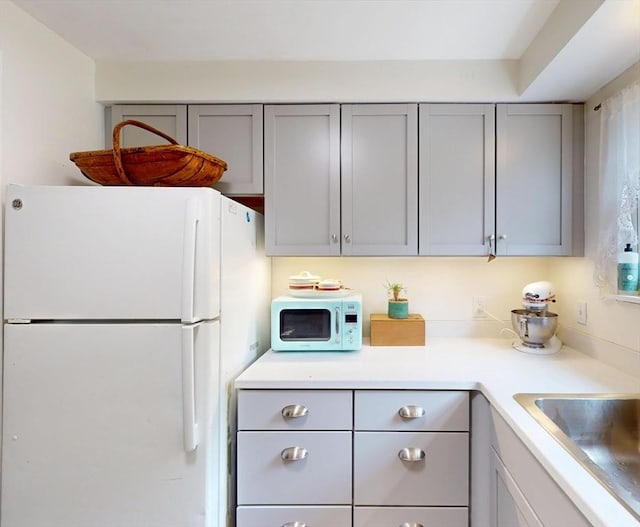 252 W St Unit 18, Amherst, MA 01002 - kitchen featuring white appliances, gray cabinetry, light countertops, and a sink