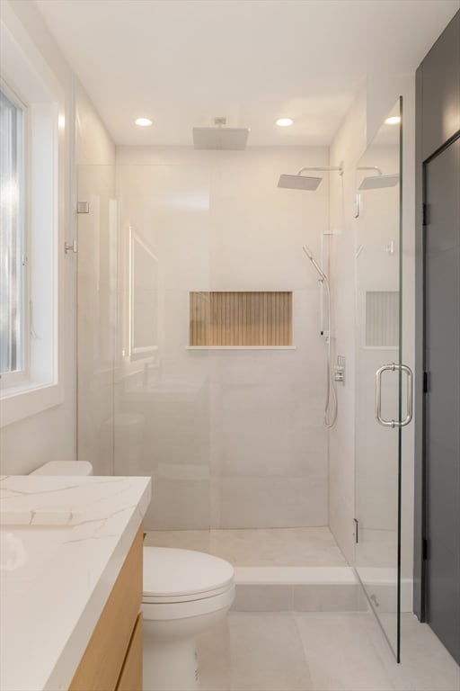 bathroom with vanity, tile patterned floors, toilet, and a shower with door