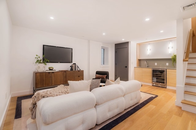 living room with beverage cooler, sink, and light hardwood / wood-style floors