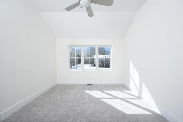 carpeted spare room with ceiling fan and vaulted ceiling