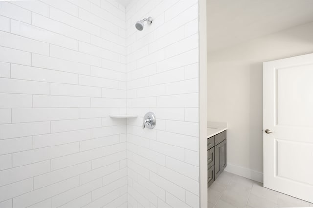 bathroom featuring tile flooring, tiled shower, and vanity