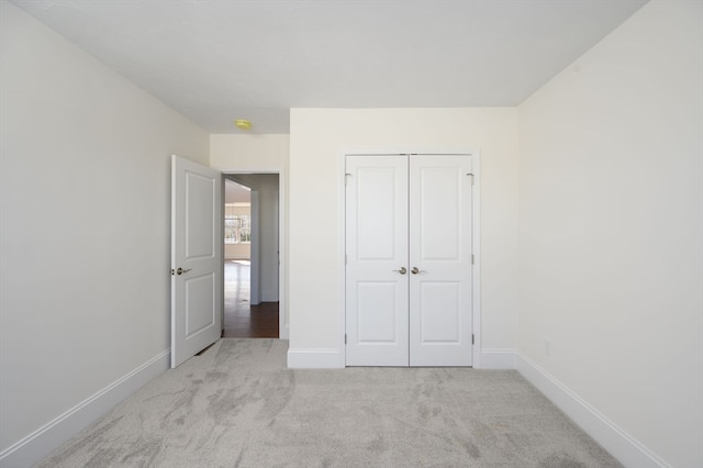 unfurnished bedroom featuring light carpet and a closet