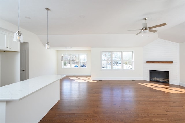 unfurnished living room with brick wall, ceiling fan, a fireplace, dark wood-type flooring, and lofted ceiling