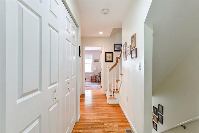 corridor featuring stairs, recessed lighting, baseboards, and light wood-style floors
