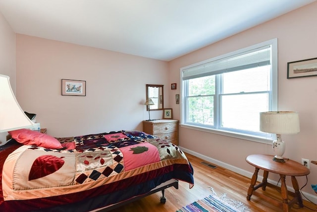 bedroom featuring baseboards, wood finished floors, and visible vents