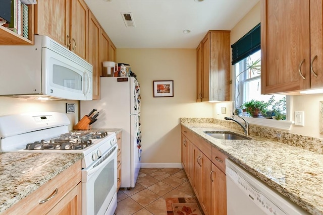 kitchen featuring light stone countertops, a sink, light tile patterned floors, baseboards, and white appliances