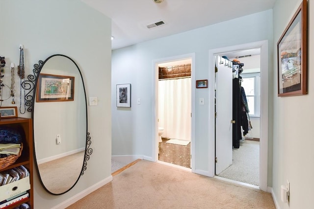 corridor with carpet flooring, baseboards, and visible vents