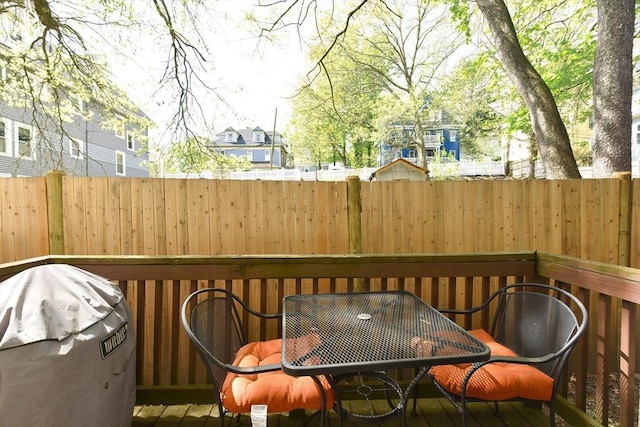 wooden terrace featuring a fenced backyard, outdoor dining space, and area for grilling