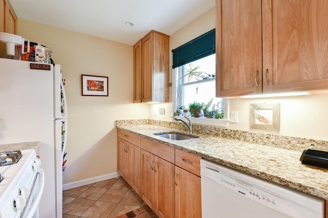 kitchen with a sink, light stone counters, light tile patterned floors, and white appliances