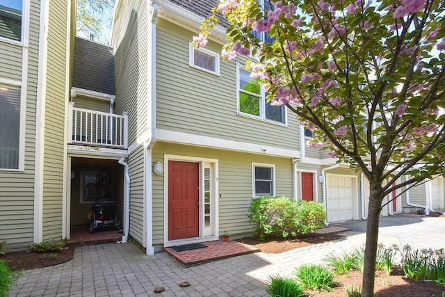 multi unit property featuring roof with shingles, an attached garage, and a balcony