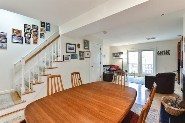 dining space featuring stairway, wood finished floors, and visible vents