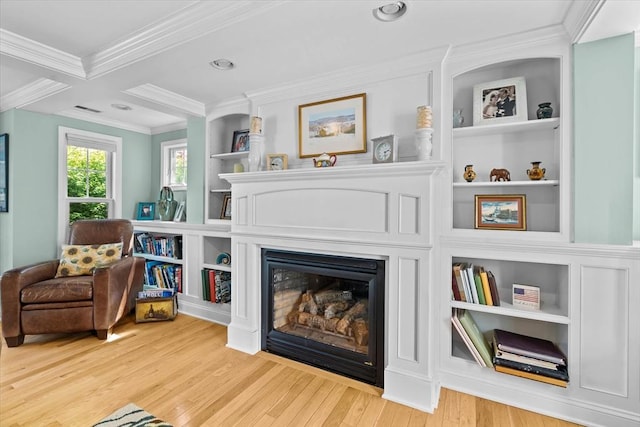 living area featuring crown molding, wood finished floors, a glass covered fireplace, and recessed lighting