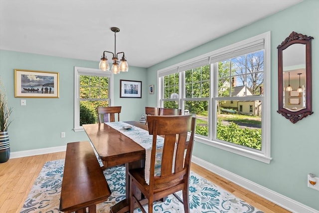 dining room featuring a chandelier, light wood finished floors, and baseboards