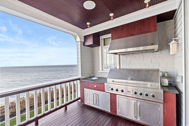 wooden deck with area for grilling, sink, a water view, and exterior kitchen