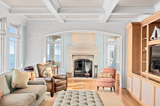 interior space featuring coffered ceiling, a large fireplace, a water view, and light hardwood / wood-style flooring