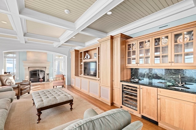 living room featuring light wood-type flooring, coffered ceiling, beverage cooler, indoor wet bar, and beam ceiling