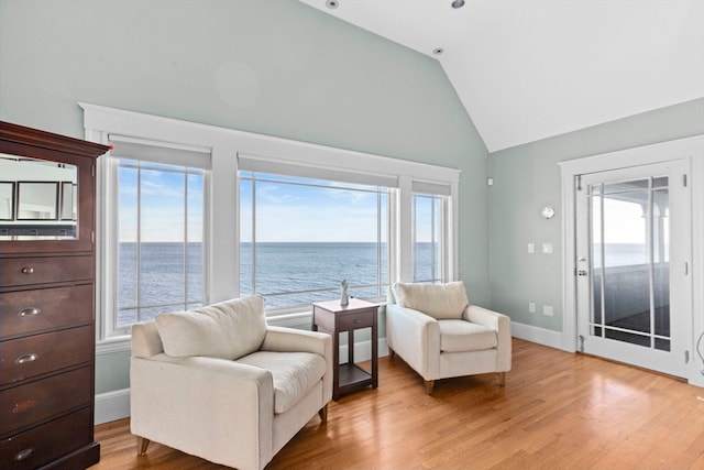 living area with a water view, high vaulted ceiling, and light hardwood / wood-style floors