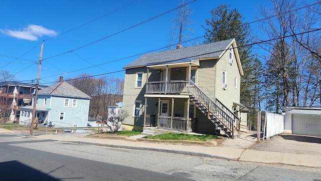 view of front of house with stairway, aphalt driveway, a shingled roof, an outbuilding, and a porch