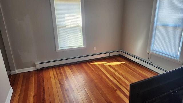 unfurnished room with hardwood / wood-style floors, baseboard heating, and plenty of natural light