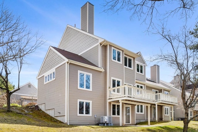 rear view of house with a wooden deck, central air condition unit, a chimney, and a yard