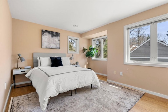 bedroom with visible vents, baseboards, and wood finished floors