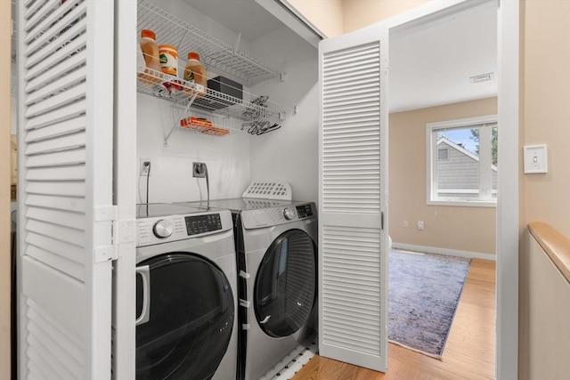 laundry area featuring baseboards, washing machine and dryer, laundry area, and light wood finished floors