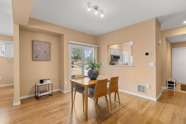 dining space featuring visible vents, baseboards, and light wood finished floors