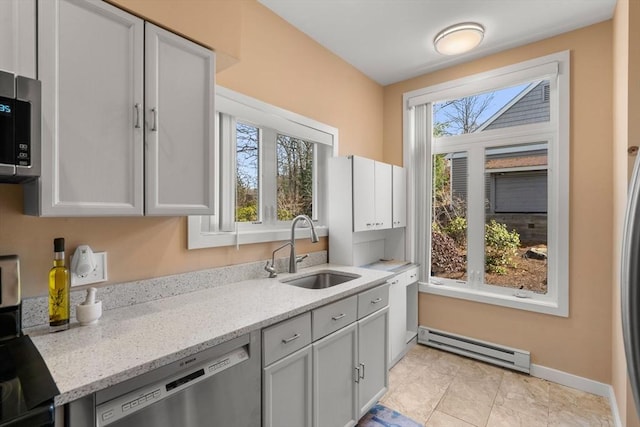 kitchen featuring appliances with stainless steel finishes, light stone countertops, a baseboard heating unit, and a sink