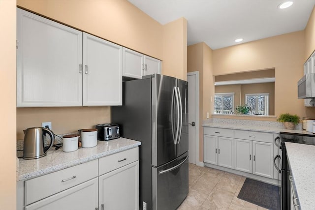 kitchen with light stone counters, recessed lighting, appliances with stainless steel finishes, and white cabinetry