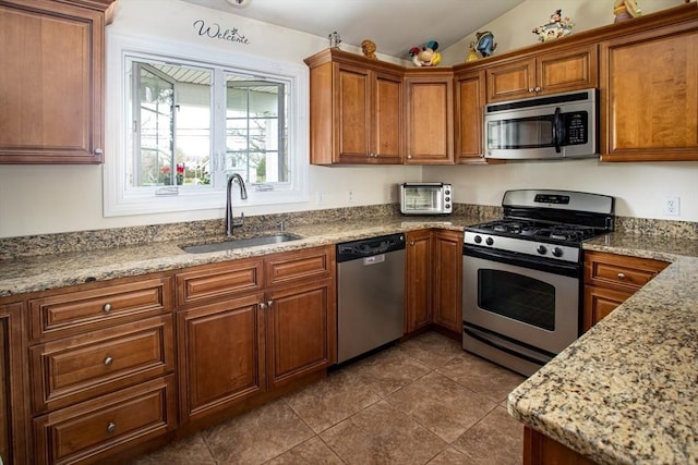 284 Hortonville Rd, Swansea, MA 02777 - kitchen with stainless steel appliances, a sink, brown cabinetry, lofted ceiling, and dark tile patterned flooring