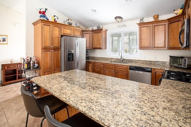 284 Hortonville Rd, Swansea, MA 02777 - kitchen featuring appliances with stainless steel finishes, a sink, brown cabinetry, vaulted ceiling, and light tile patterned floors