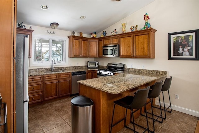 284 Hortonville Rd, Swansea, MA 02777 - kitchen with stainless steel appliances, a sink, a peninsula, brown cabinetry, and a kitchen bar