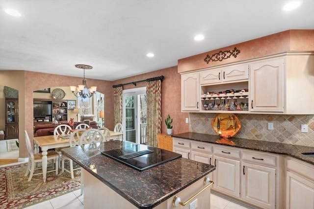 kitchen with light tile patterned floors, dark stone counters, black electric stovetop, and a chandelier