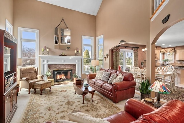 living area with arched walkways, a high ceiling, a fireplace, and carpet