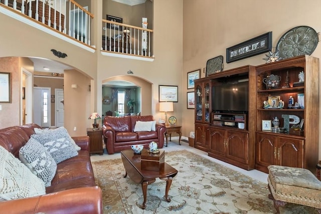 carpeted living area with arched walkways and baseboards