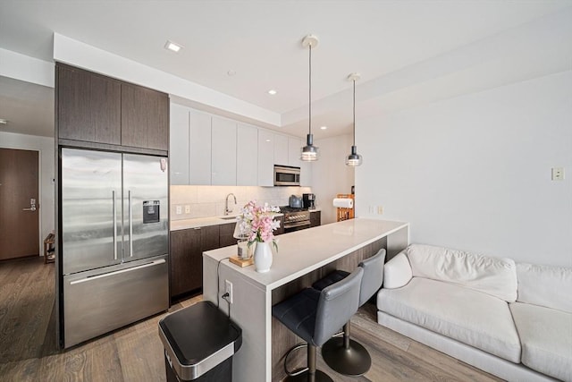 375 Canal St Unit 1109, Somerville, MA 02145 - kitchen with premium appliances, a breakfast bar, wood finished floors, light countertops, and recessed lighting
