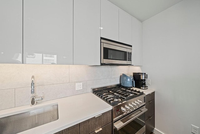 375 Canal St Unit 1109, Somerville, MA 02145 - kitchen with stainless steel appliances, white cabinetry, decorative backsplash, and light countertops