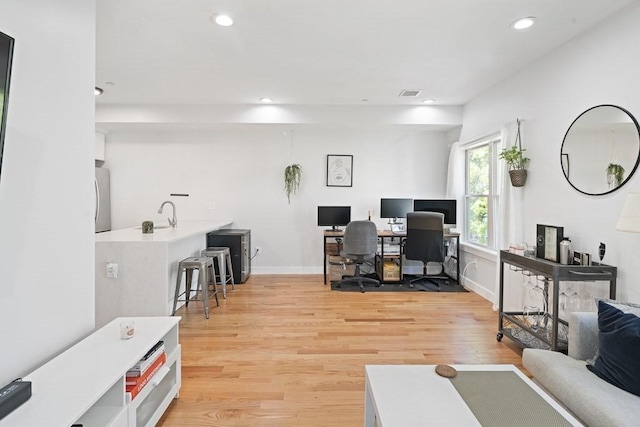 office space with light hardwood / wood-style floors and sink