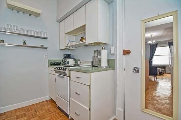 kitchen featuring white cabinetry, light parquet flooring, electric range, and an inviting chandelier