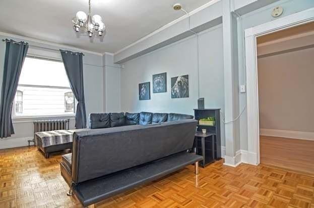 living room featuring parquet flooring, radiator heating unit, and a chandelier