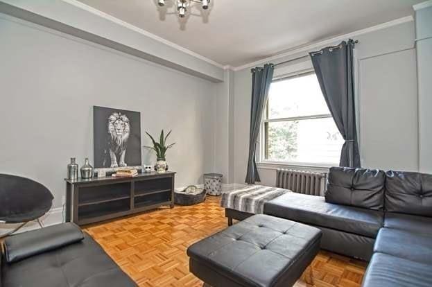 living room with parquet flooring, radiator heating unit, and ornamental molding