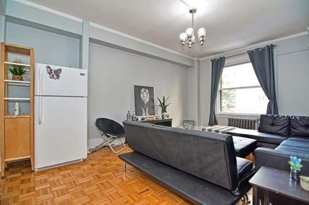 living room with radiator, crown molding, a chandelier, and light parquet floors