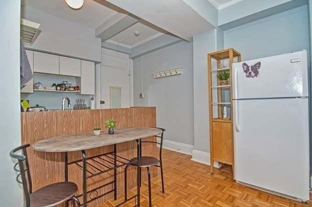 kitchen with light parquet flooring, white fridge, and white cabinets