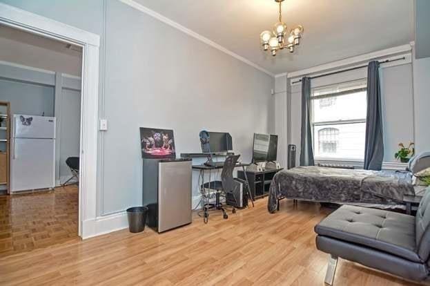 bedroom with white refrigerator, ornamental molding, light wood-type flooring, and a notable chandelier