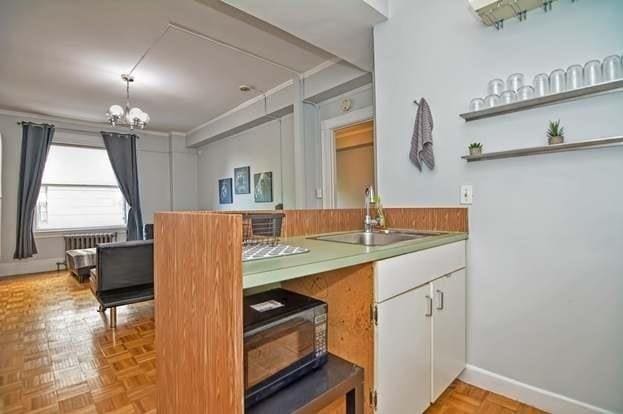 bar featuring white cabinetry, sink, a chandelier, and light parquet flooring