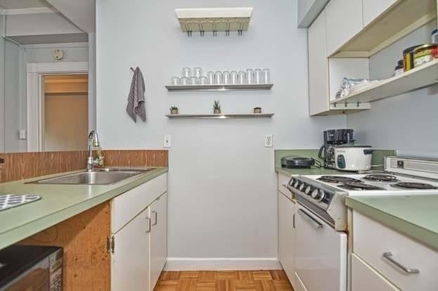 kitchen featuring white cabinetry, white range with electric cooktop, light parquet flooring, and sink