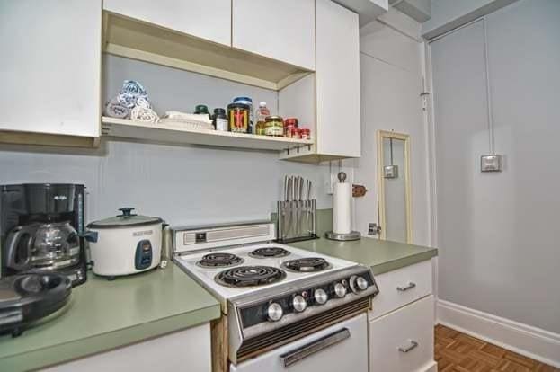 kitchen with dark parquet flooring, white electric stove, and white cabinets